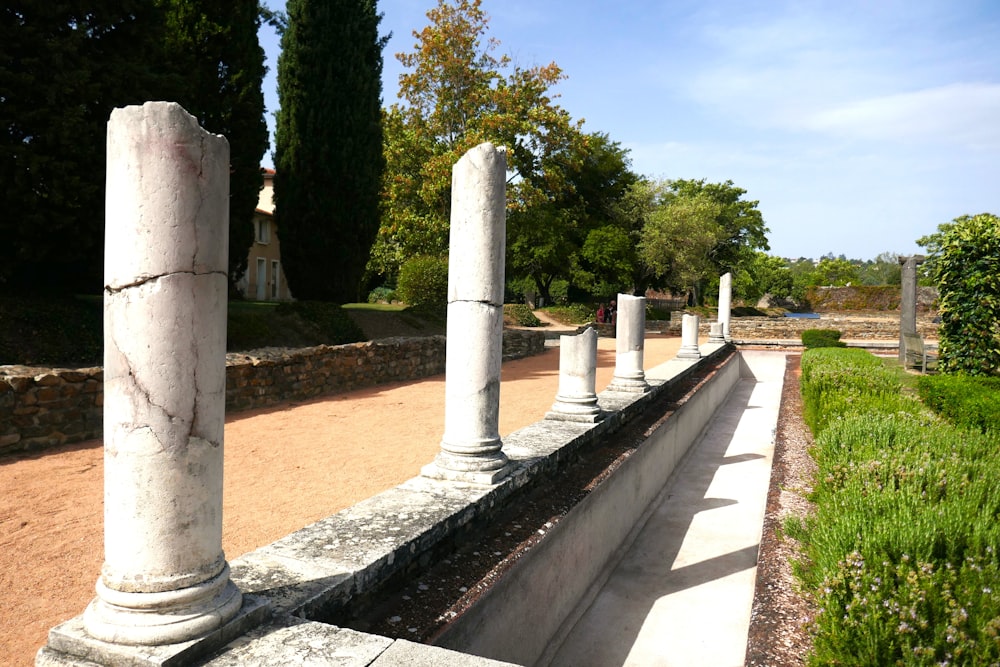 a row of white pillars sitting next to a lush green park