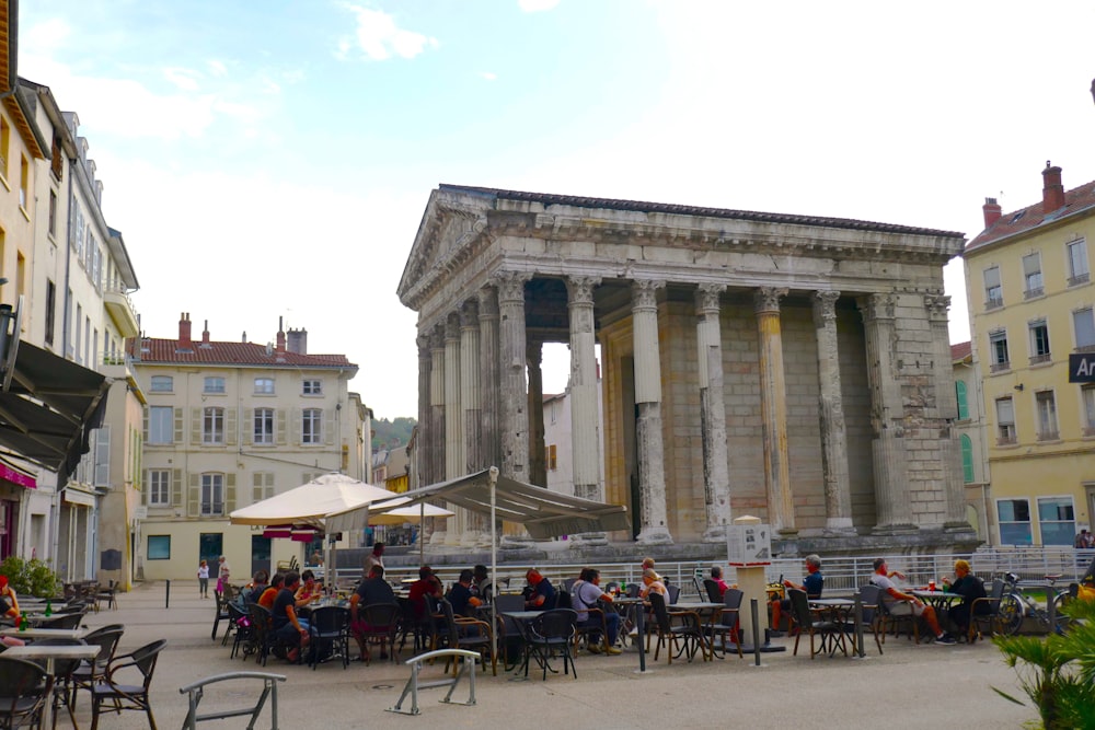 a group of people sitting at tables in front of a building