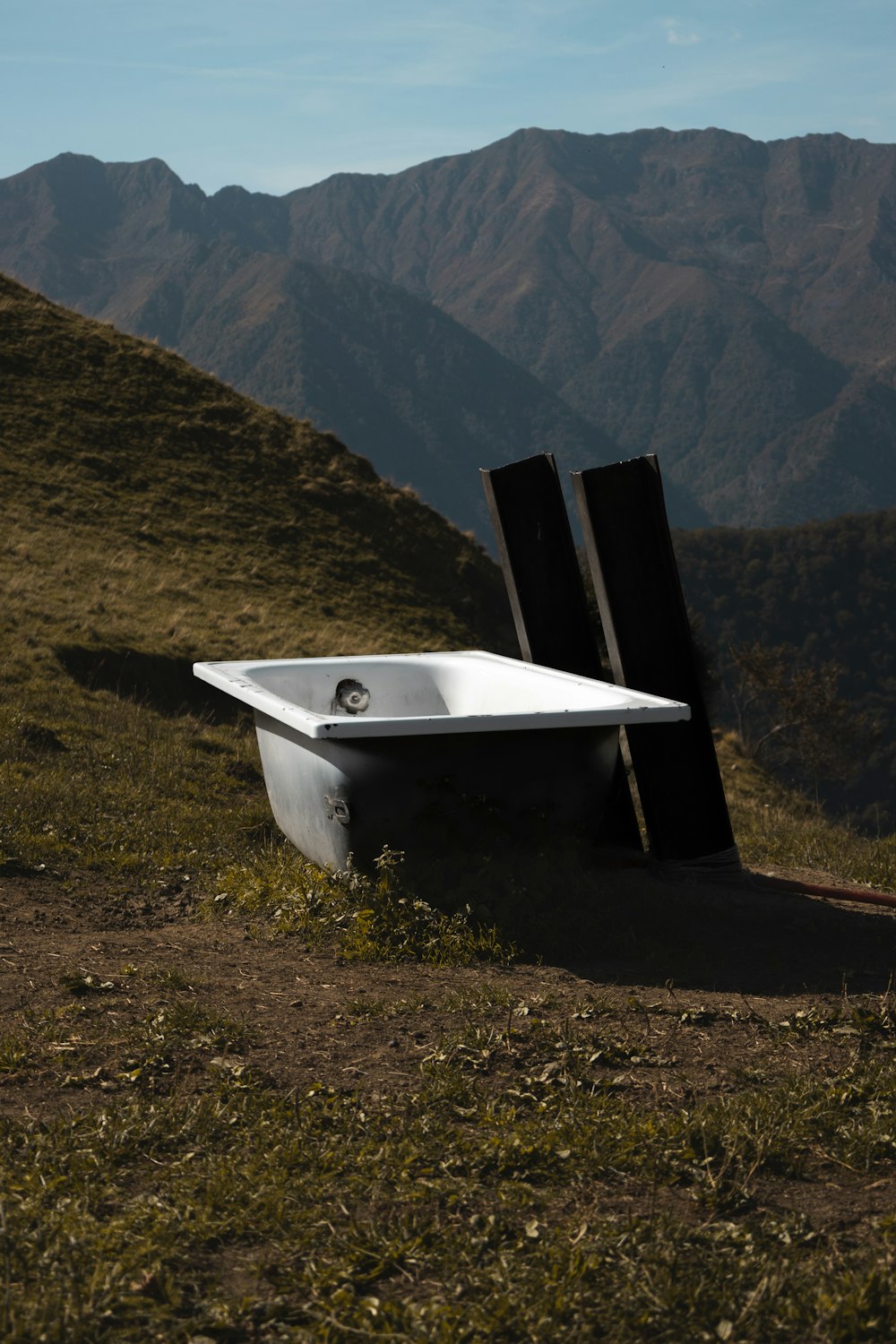 a white bath tub sitting on top of a lush green hillside