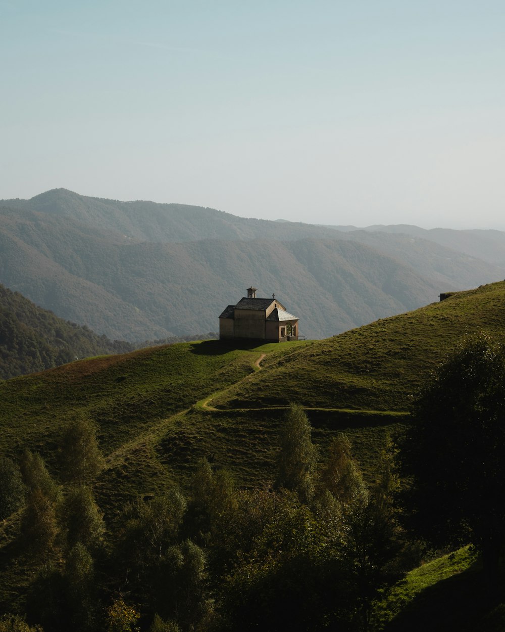 a house on a grassy hill with mountains in the background