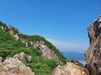 A scenic view of Garraf National Park with limestone cliffs and lush greenery under a bright blue sky.