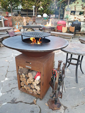 A clean and ready-to-use fire pit with accessories neatly arranged on a patio.