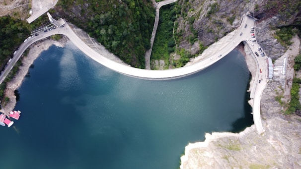 An aerial view of a massive dam structure nestled in a mountainous landscape, showcasing intricate engineering details.
