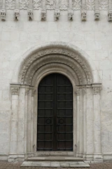 Sturdy oak door framed by a classic stone archway.