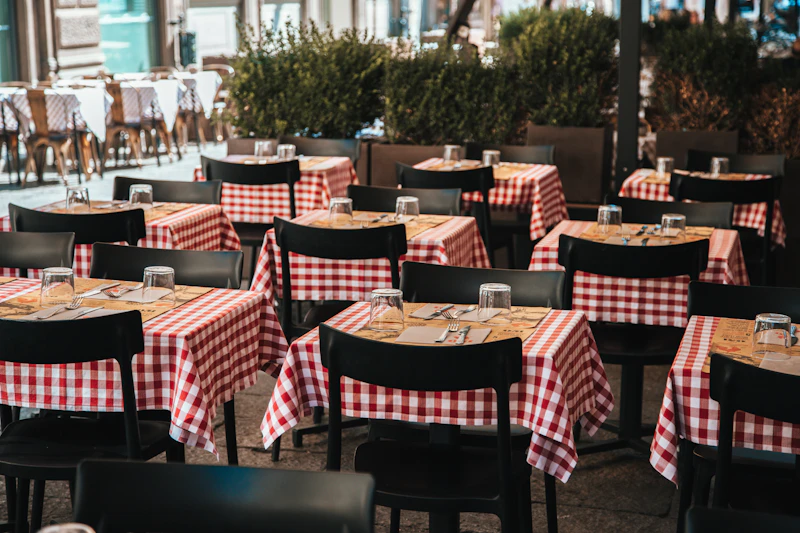 Italian trattoria interior with red-and-white checkered tablecloths, wine bottles, and warm candlelight