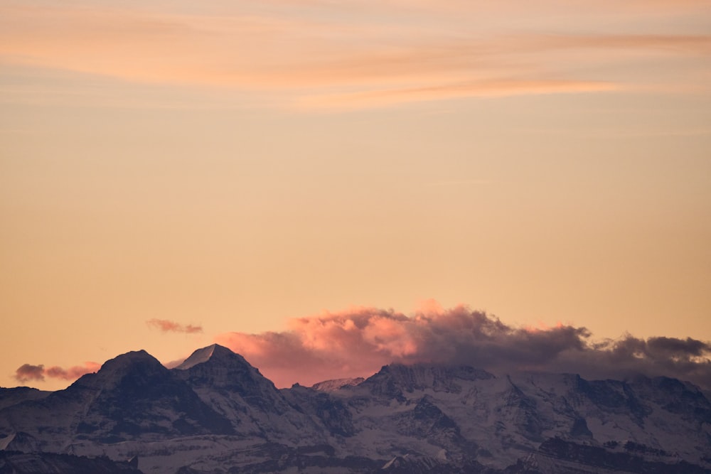 a plane flying over a mountain range at sunset