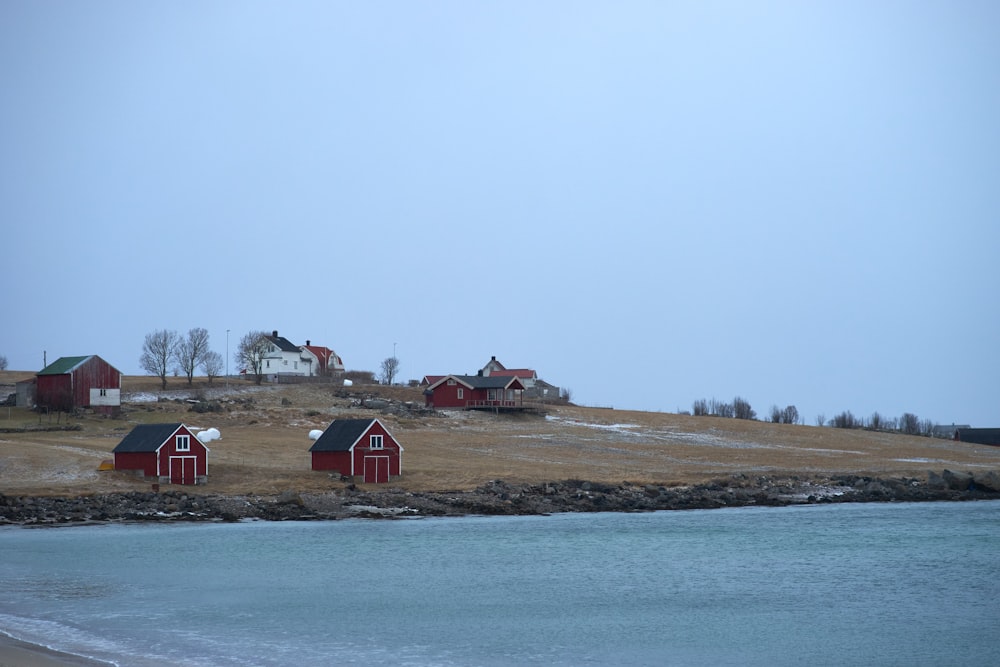 a group of red barns sitting on top of a grass covered hillside