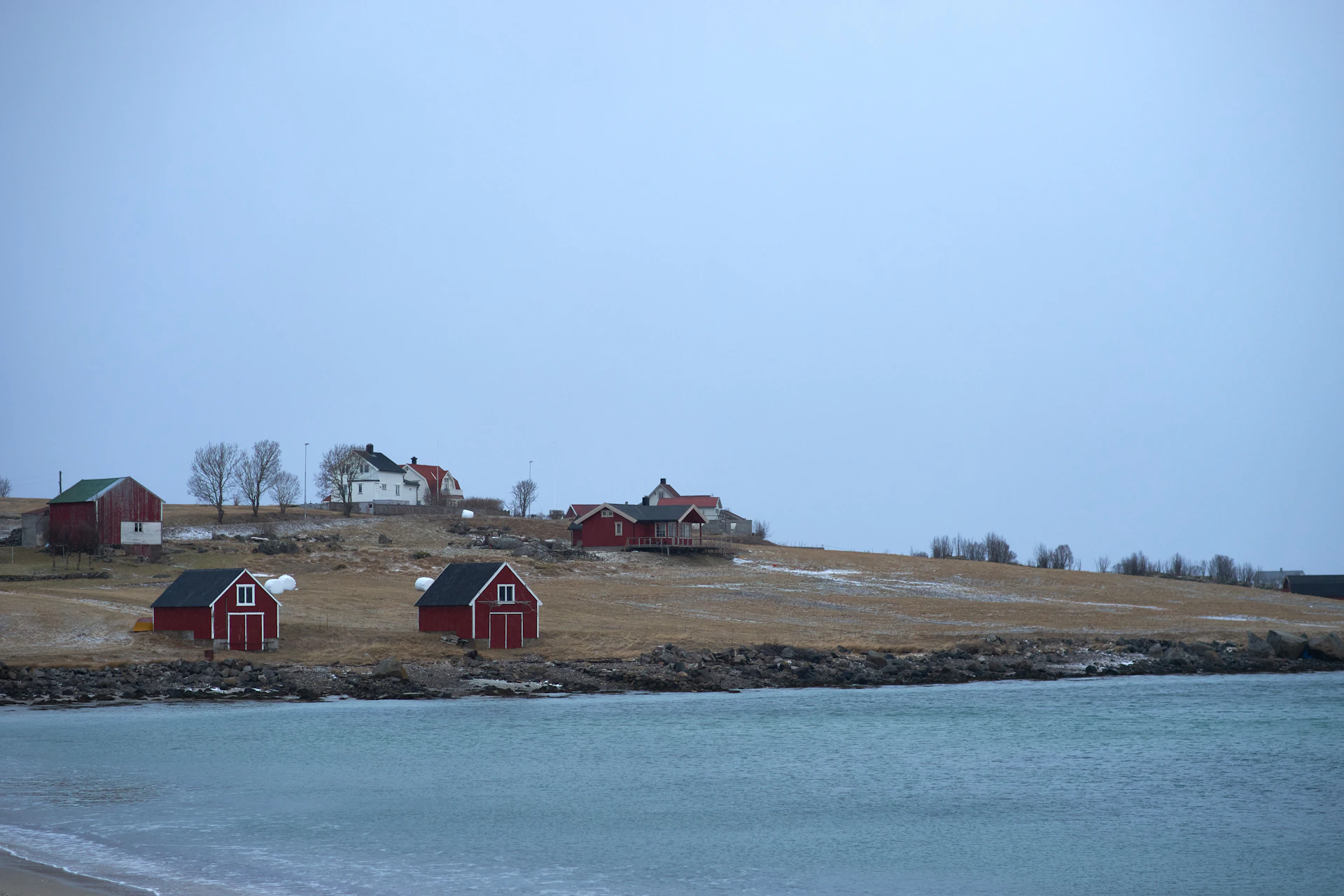 a group of red barns sitting on top of a grass covered hillside