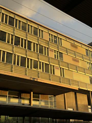 Modern corporate office building with dark glass facade and golden accents at sunset.