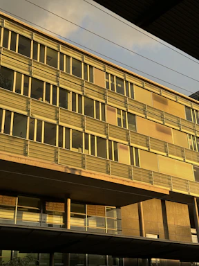 A sleek modern office building in Bahrain with golden sunlight reflecting off its glass facade.