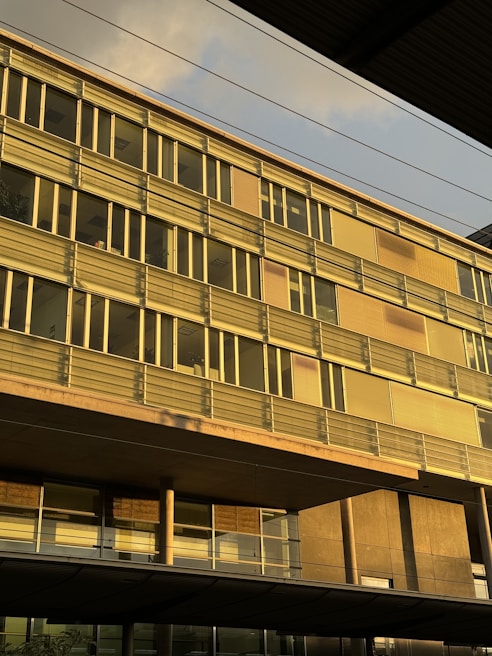 Commercial office building featuring glass facades and gold trim details during sunset