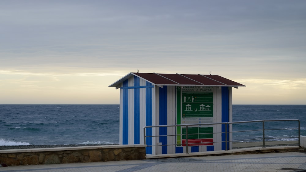 a blue and white beach hut next to the ocean
