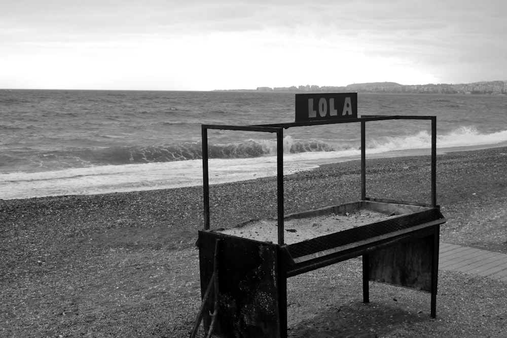 a black and white photo of a chair on the beach