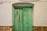 a green door with a white wall and stone floor