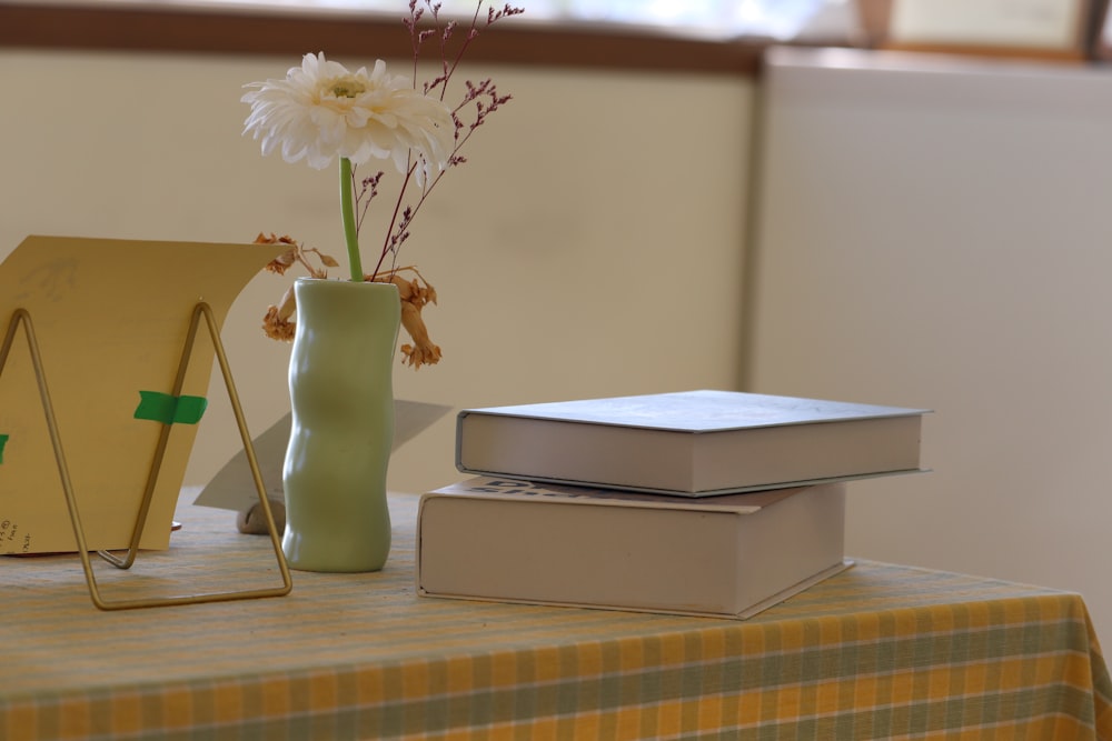 a table with a vase of flowers and two books