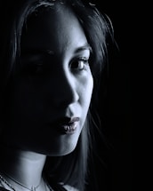A close-up of a camera lens capturing a striking portrait with dramatic lighting.