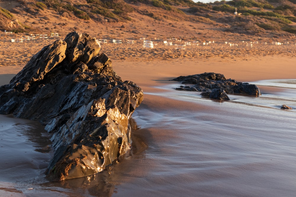 a rock sticking out of the sand on a beach