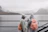 A hiker wearing a bright ripstop poncho standing on a rain-soaked trail with misty mountains in the background.