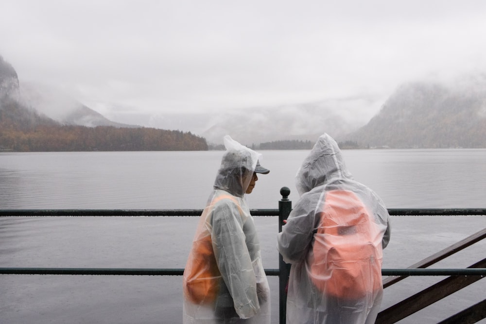 two people in raincoats looking out over a body of water
