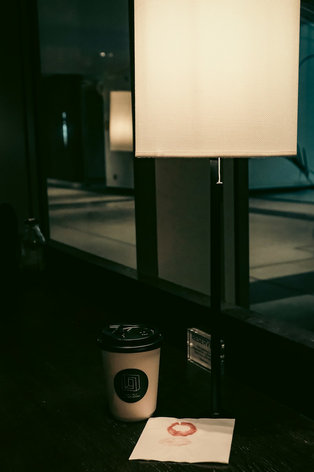 a cup of coffee next to a lamp on a table