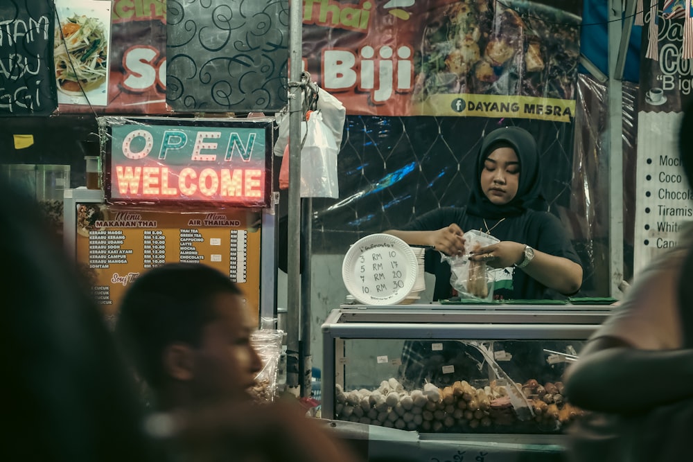 a woman standing in front of a food stand