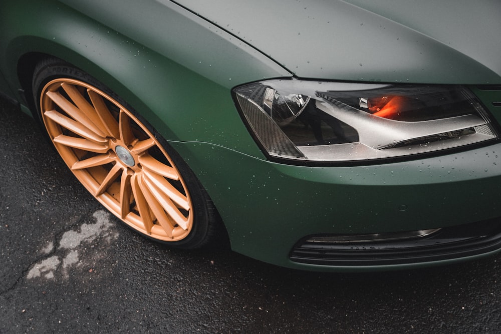 a close up of a green car with orange rims