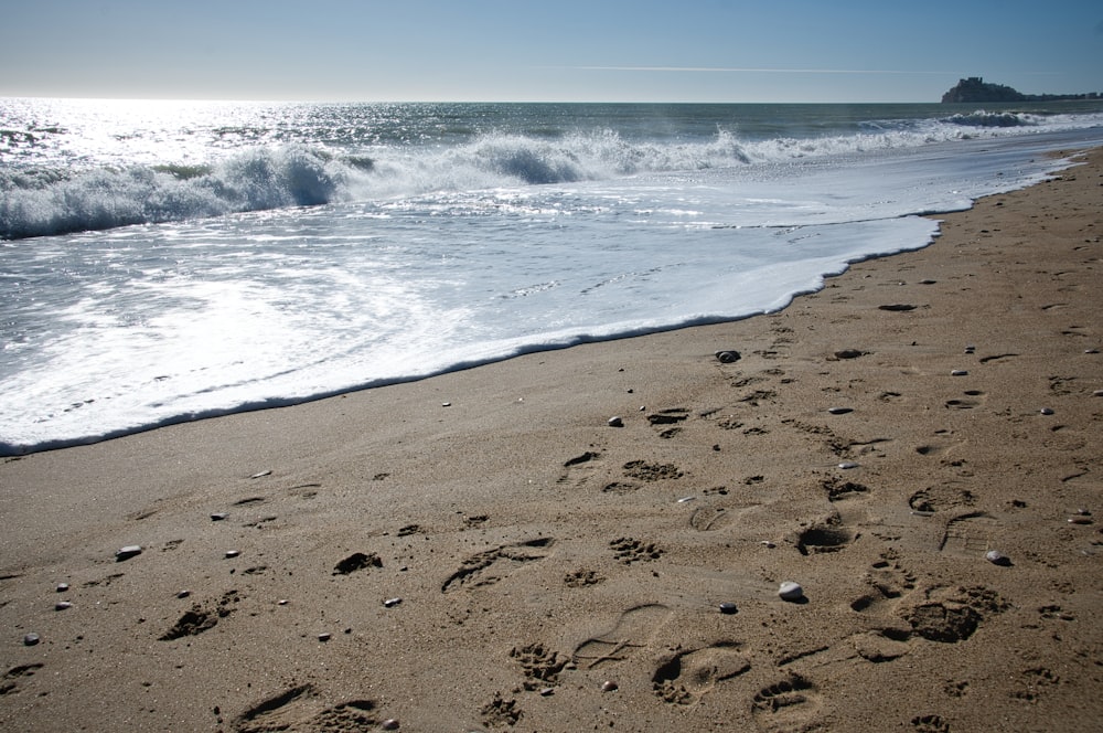 footprints in the sand on a beach next to the ocean