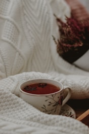 Close-up of colorful handmade crochet pieces resting beside soothing herbal tea.