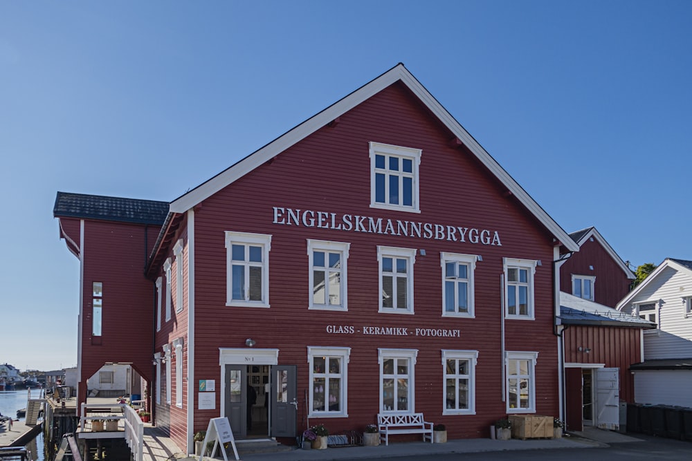 a red building with white windows next to a body of water