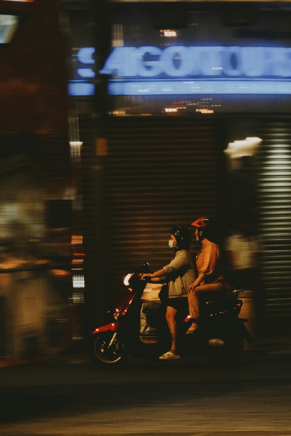 a man and a woman riding a motorcycle down a street