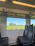 A cozy train cabin interior with large windows showing lush green landscapes.