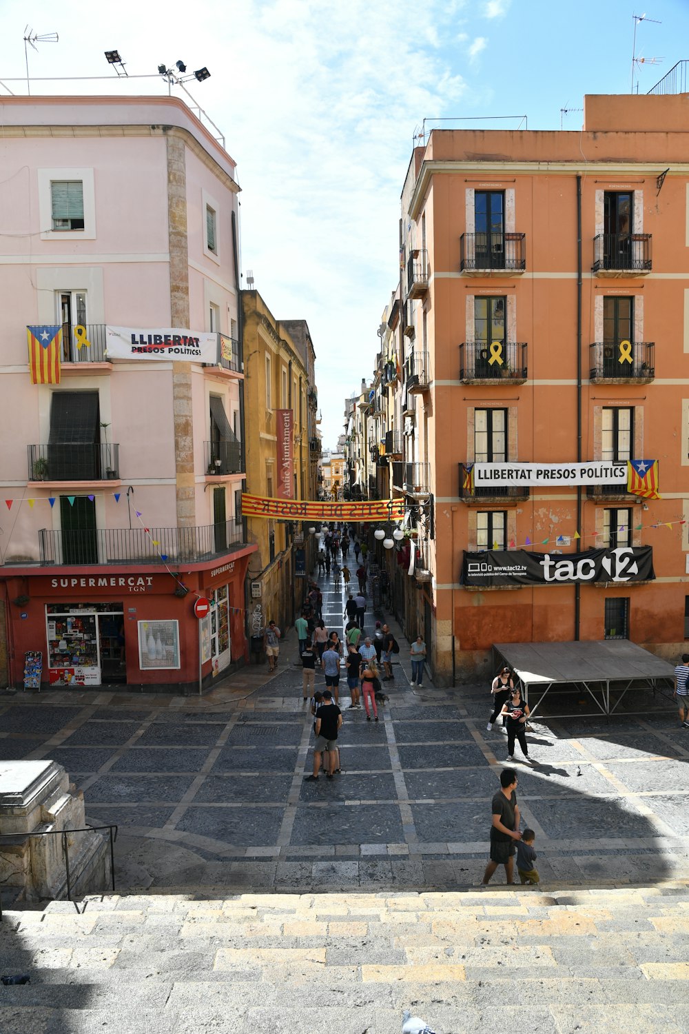 a group of people walking down a street next to tall buildings