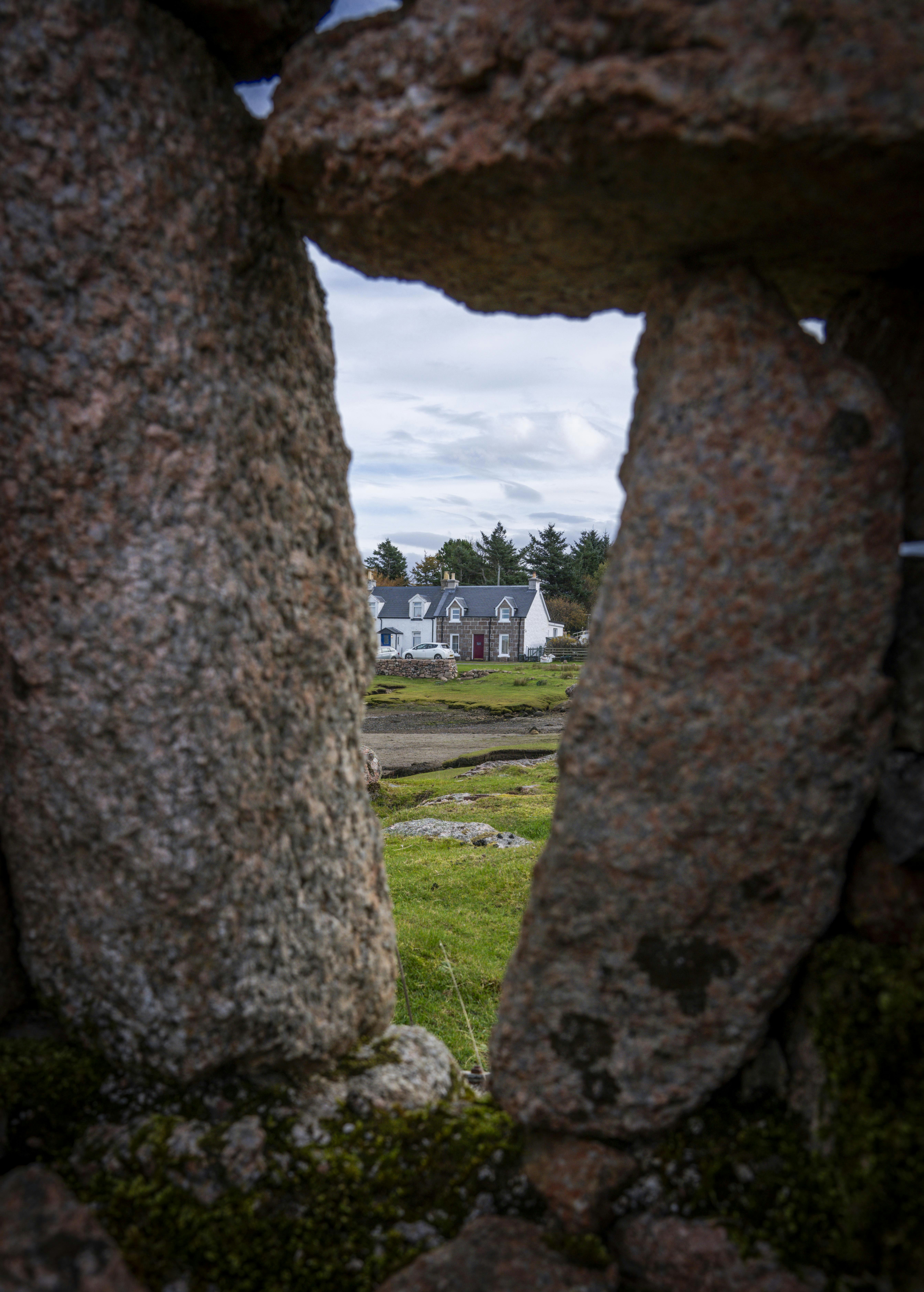 A stone wall with a house in the background