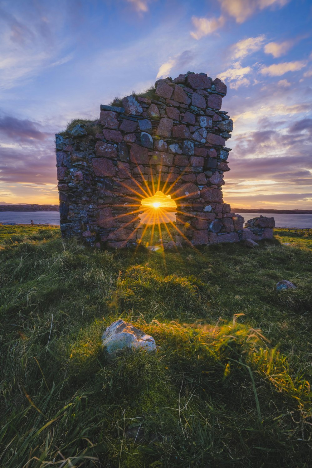 a stone structure with the sun setting behind it