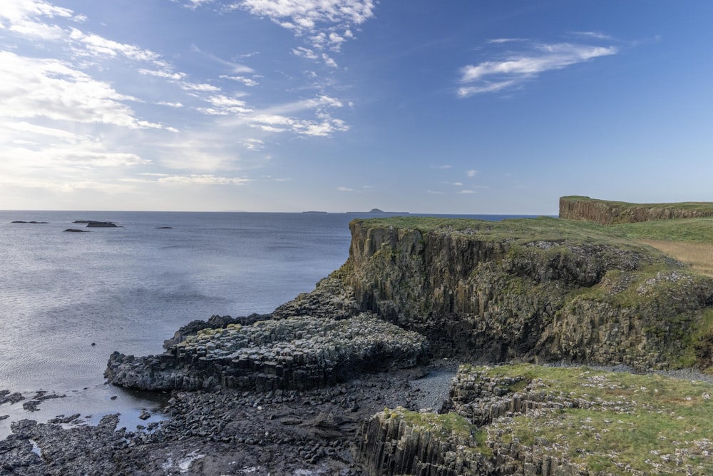 a rocky cliff overlooks the ocean on a sunny day