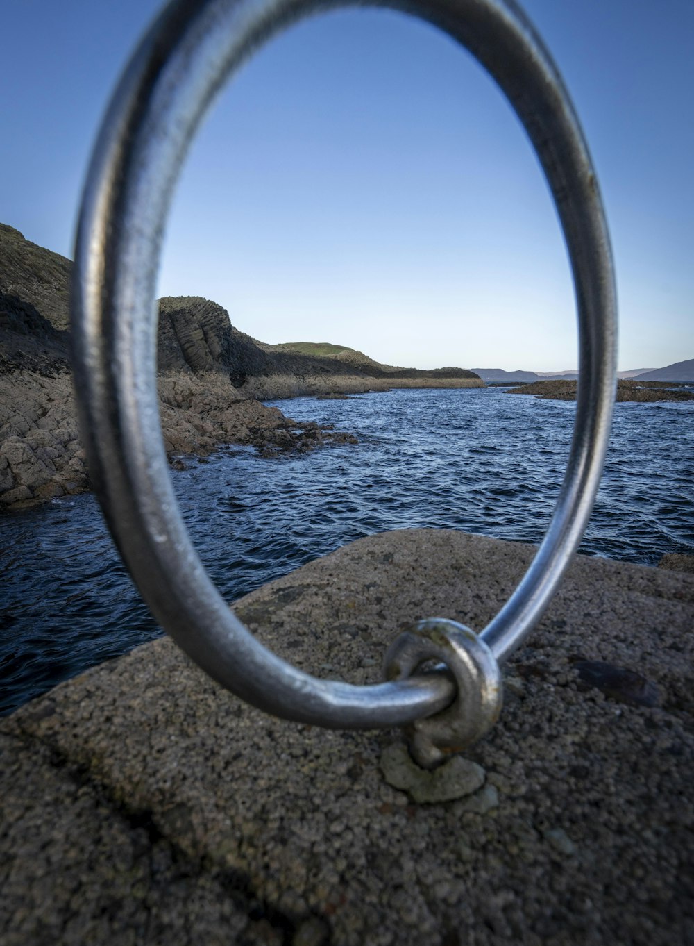 a view of a body of water through a metal ring