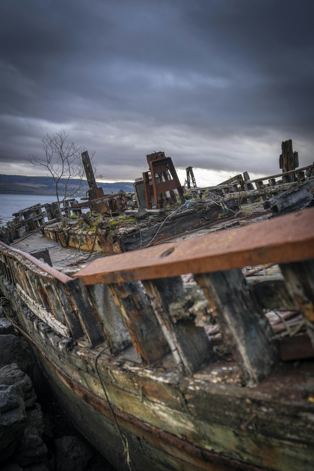 an old boat sitting on top of a rocky beach