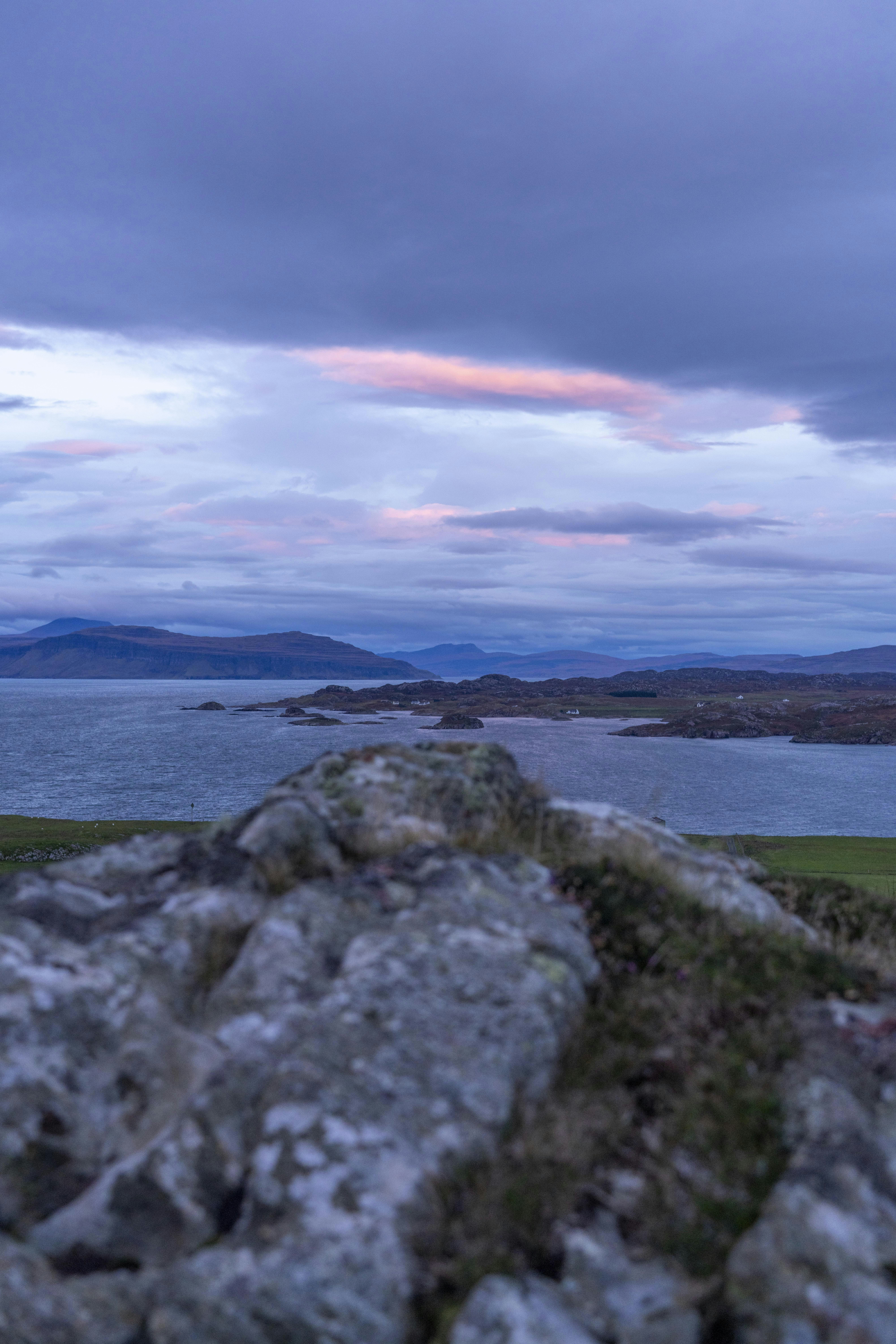 a bench sitting on top of a large rock next to a body of water
