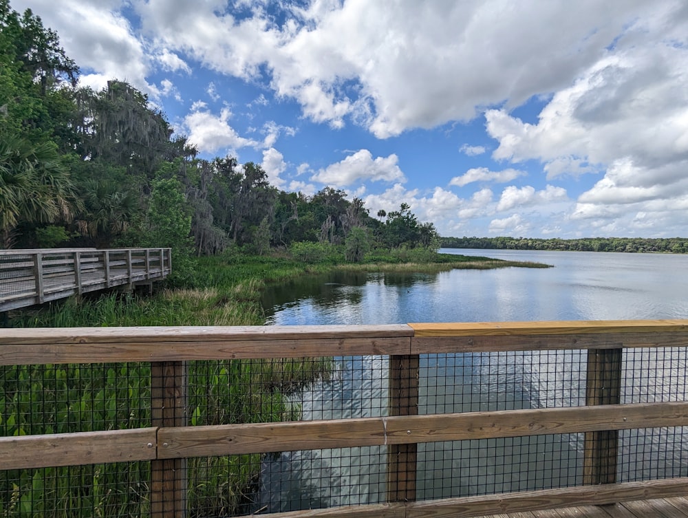 a wooden bridge over a river next to a lush green forest