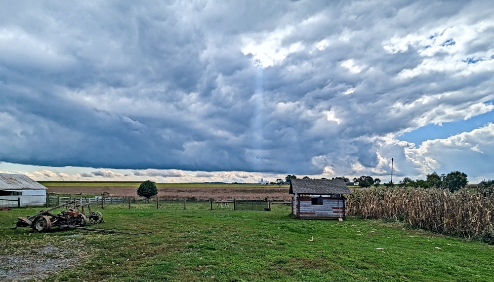 a farm with a barn and a cornfield under a cloudy sky