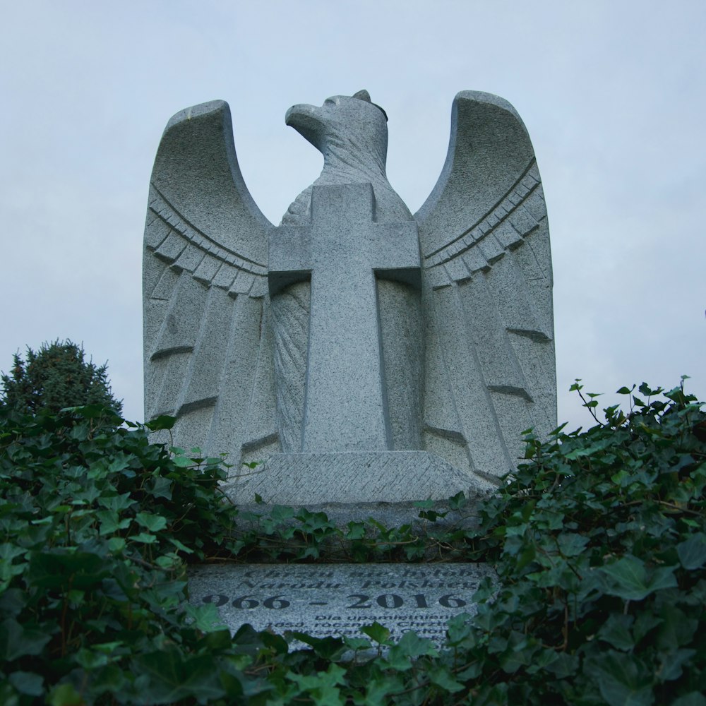 a statue of an eagle surrounded by greenery