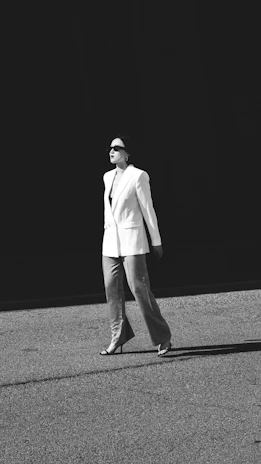 A stylish model walking confidently in a chic blazer and tailored pants, highlighted by soft evening light.