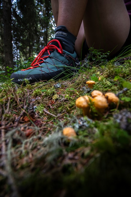 Close-up of a runner’s feet in trail shoes on a mossy forest floor during a yoga pose