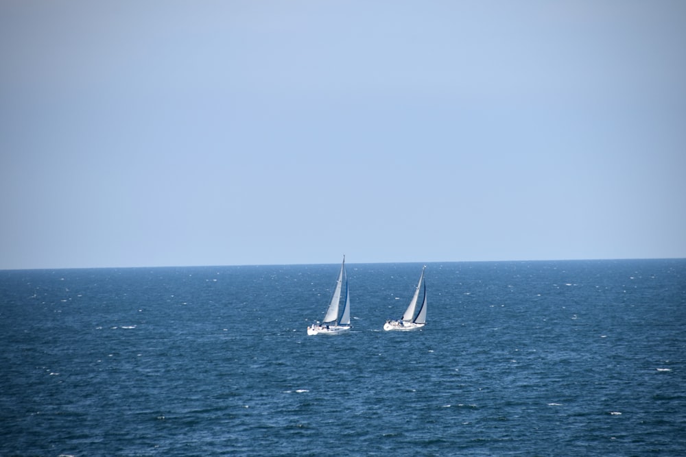 two sailboats in the middle of the ocean