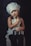 A young child wearing a chef's hat and a white apron poses with a small cooking pot and a kitchen utensil. The child has an inquisitive expression against a dark background, sitting on a cushioned stool.