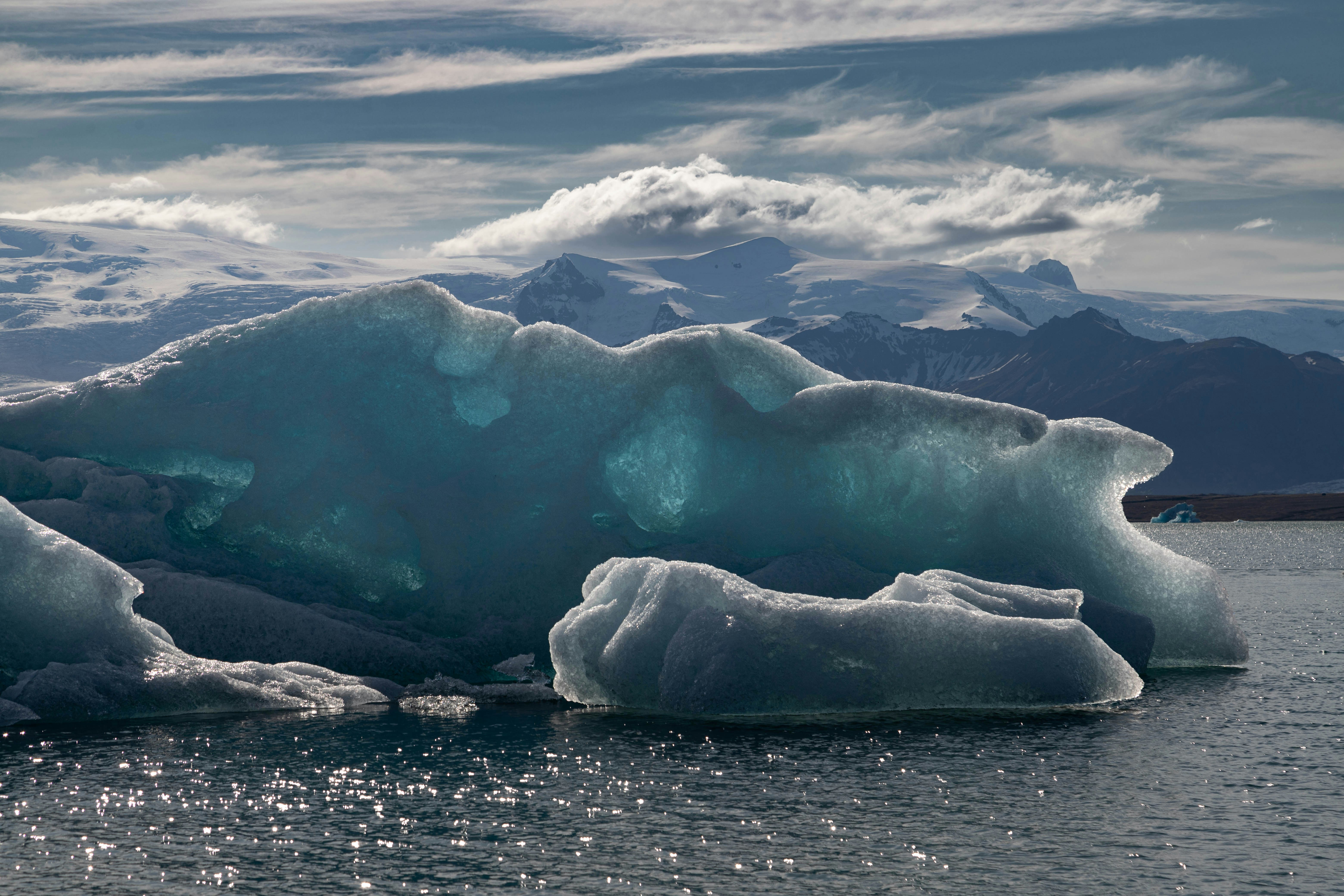A large iceberg floating on top of a body of water photo – Free Útsýni