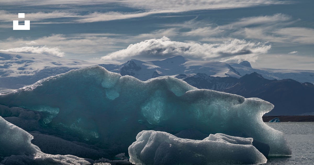 A large iceberg floating on top of a body of water photo – Free Útsýni