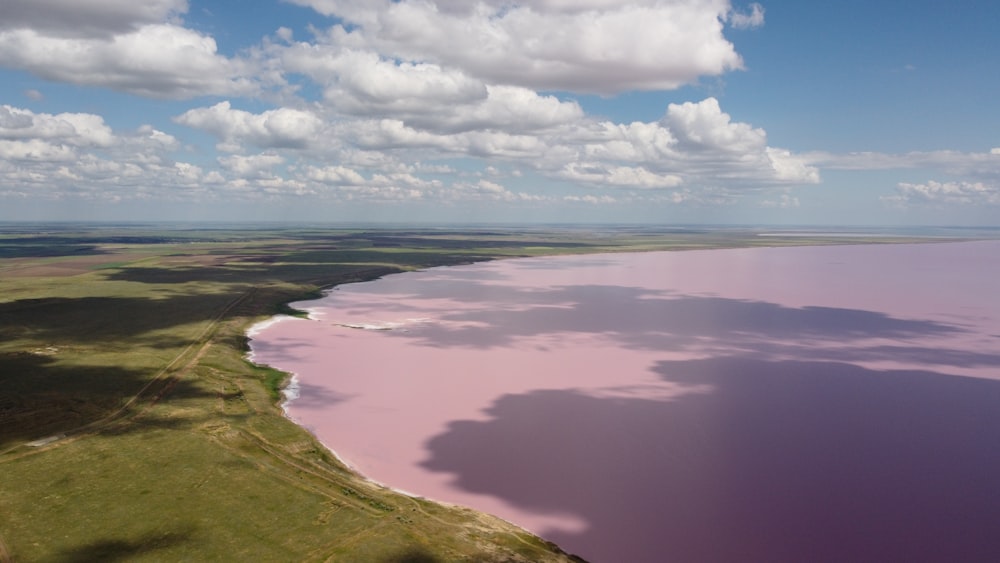 a large body of water surrounded by lush green fields