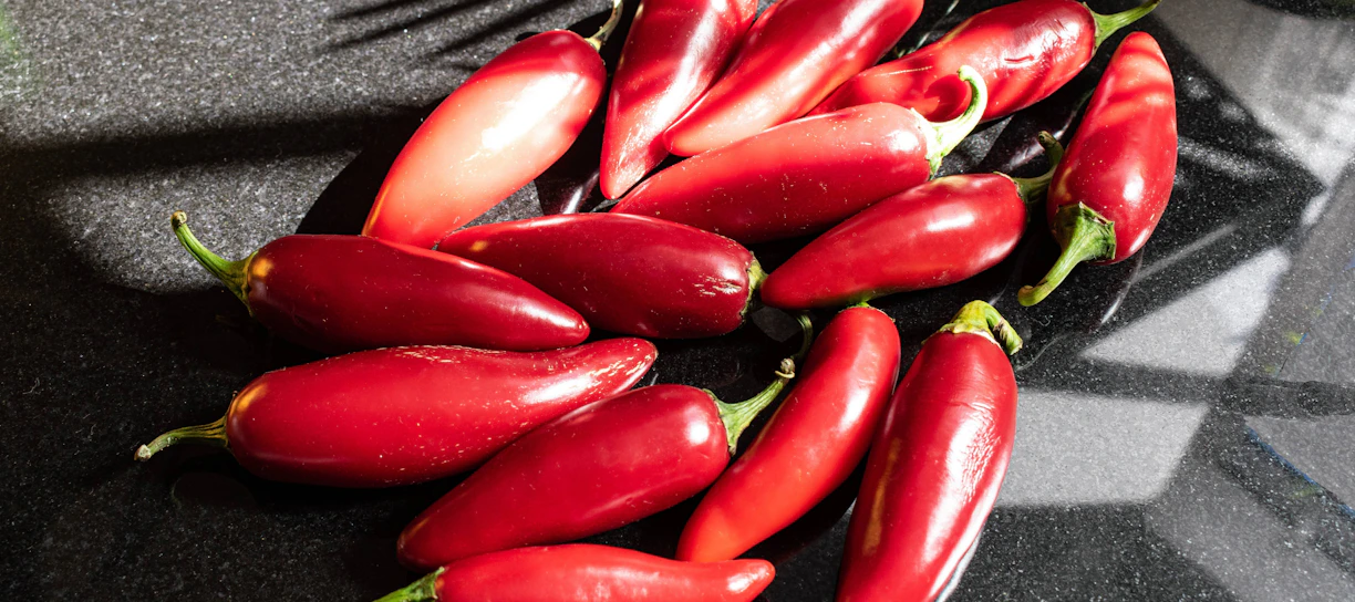 a pile of red peppers sitting on top of a counter