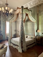 Elegant four-poster bed draped with sheer curtains in a softly lit room.